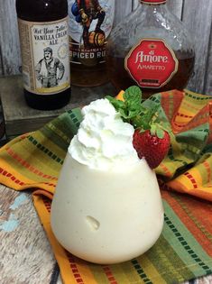 a bottle of booze next to a strawberry and whipped cream