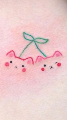 a close up of a person's chest with two cats on it and a green bow