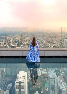 a woman standing on top of a tall building looking at the city from above her