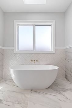 a white bath tub sitting next to a window in a bathroom under a skylight