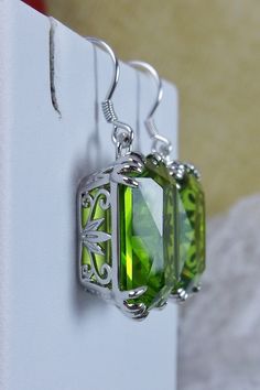 Simulated Green Peridot Earrings Description LUV Design#109 Made to Order These are lovely Art Nouveau Inspired sterling silver filigree earrings. The silver of these earrings has a gorgeous Antique patina to it. These 26ctw flawless rectangle-cushion-cut man-made/simulated Green Peridot gems are 18mm (just over 3/4th of an inch) by 13mm (1/2 inch) in size each. The earrings are 1 3/8th inches long. Notice the beautiful swirl floral filigree of the settings. This is a well made beautiful pair of Elegant Lime Green Earrings For Formal Events, Silver Earrings For Wedding With May Birthstone, Silver Wedding Earrings For May Birthstone, Elegant Nickel-free Green Jewelry, Green Jewelry With Intricate Design For Gift, Silver Earrings For Wedding, May Birthstone, Elegant Lime Green Earrings For Formal Occasions, Green Sterling Silver Jewelry With Intricate Design, Intricate Green Jewelry For Gift