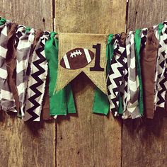 a football themed banner hanging on a wooden wall with burlocks and ribbons around it