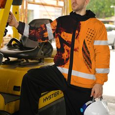 a man sitting on top of a forklift wearing an orange and black hoodie