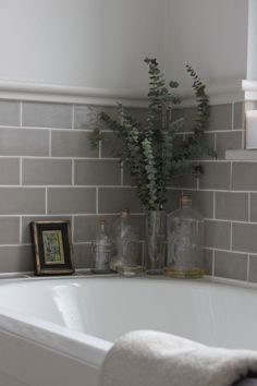 a white bath tub sitting in a bathroom next to a framed photo and flowers on the counter