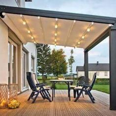 an outdoor deck with chairs and lights on it