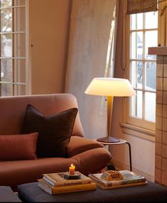 a living room filled with furniture and a lamp on top of a table next to a window