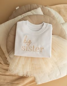 TUTU SOLD separately- these can be found in our store.  Beige Thread matches the cream tutu, dusty pink will match the pink tutu.  These sweatshirts are true to size, if you like a move oversized fit to wear with leggings I would suggest to size up.  The baby sizes (up to 24-36Months) include poppers at the top for ease, and they are also a lightweight sweatshirt which is perfect for spring. Age 3-4+ are fleece lined.  FRENCH TERRY, 85% COTTON - ORGANIC RING SPUN COMBED, 15% POLYESTER - RECYCLED, FABRIC WASHED, LIGHT SUEDED, 280 G/M² This jumper  is completely free from dyes, which means that each garment reflects the true colour of the cotton plant itself. The fabric is textured with tiny specks of the original plant, including seed particles, adding to its beauty and authenticity.  Care: White Custom Embroidered Tops For Birthday, White Long Sleeve Tops For Baptism, White Long Sleeve Tops For Gender Reveal, White Long Sleeve Tops For First Birthday, Sibling Baby Announcement, Baby Announcement Big Sister, Sibling Baby Announcements, Big Sister Announcement, Sister Announcement