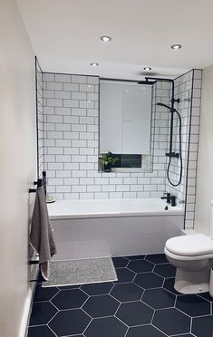 a white toilet sitting next to a bath tub in a bathroom on top of a black and white floor