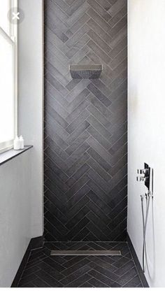 a bathroom with black and white herringbone tile on the shower wall, along with a window