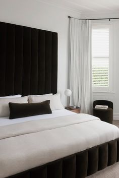 a bedroom with a large bed and black headboard