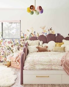 a bed with lots of pillows on top of it in a room filled with flowers