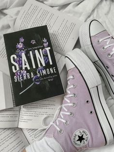 the book saint by sierra simone is laying next to two pairs of converse shoes