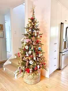 a small christmas tree in a basket on the floor next to stairs with ornaments hanging from it