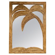 a mirror that is made out of wood and has palm leaves on it, as well as the frame