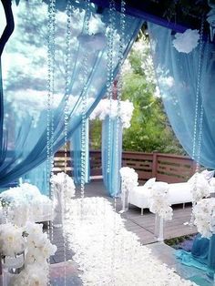 an outdoor wedding setup with white flowers and blue drapes