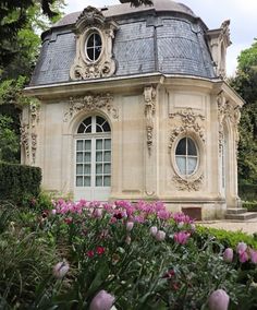 an old building surrounded by flowers and greenery