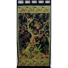 an embroidered wall hanging with trees and animals on it's sides, surrounded by foliage