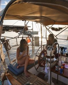 two women sitting on the deck of a sailboat in the ocean at sunset or sunrise