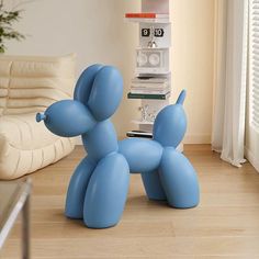 a blue balloon dog sitting on top of a hard wood floor next to a window