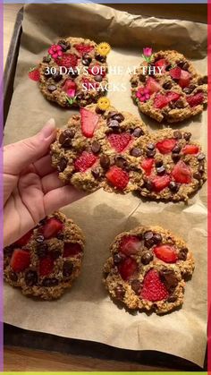 someone is holding up some cookies with strawberries and chocolate chips