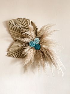 a decorative wall decoration with blue flowers and feathers on the top of it, against a white background