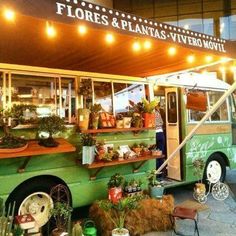 a food truck parked in front of a building with plants on the outside and lights above it