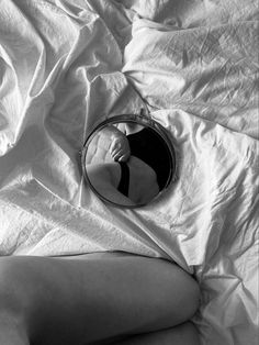 a woman's reflection in a mirror on top of a white sheet covered bed