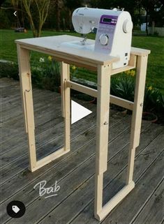 a sewing machine sitting on top of a wooden table next to a grass covered field