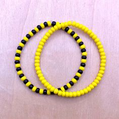 two yellow and black beaded bracelets sitting on top of a table