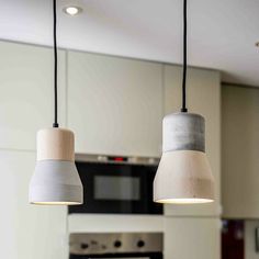 two pendant lights hanging from a kitchen ceiling over a stove top oven and countertop