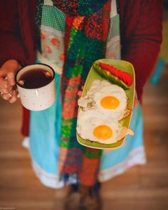 a person holding a plate with two eggs on it and a cup of coffee in their hand