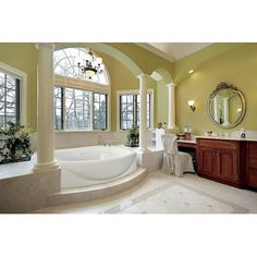 a large bathroom with an oval tub and double sinks in the center, surrounded by windows