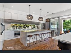 a large kitchen with an island and bar stools in the center, surrounded by glass doors