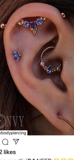 an ear piercing with three different colored stones on top of it and two smaller ones behind the ear