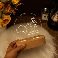 a person is holding up a glass ornament with the outline of australia on it