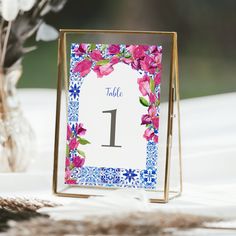 a table number is displayed in front of a vase with flowers on the tablecloth