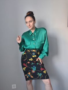 a woman in a green shirt and floral skirt posing for the camera with her hand on her hip