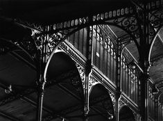 black and white photograph of an ornate building with arches, pillars and lights on the ceiling