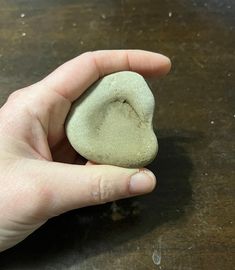 a hand holding a rock on top of a wooden table