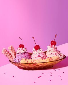 three ice cream sundaes in a bowl with cherries on top