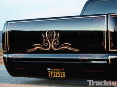 the front end of an old black car with gold designs on it's hood