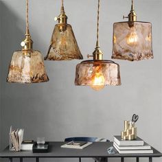 three glass pendant lights hanging over a table