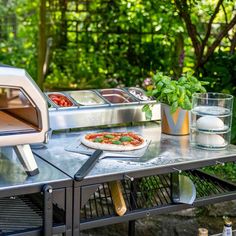 a pizza is being cooked on an outdoor grill in the sun with other food items nearby