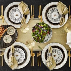 an overhead view of a table set with plates and silverware, gold napkins