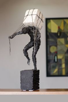 a sculpture of a man holding a bag on top of a block of rock in front of a painting