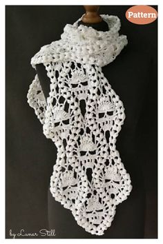 a white crocheted scarf hanging on a mannequin