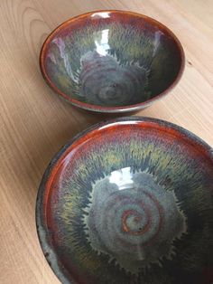 two bowls sitting on top of a wooden table next to each other with different colors