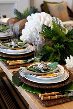 the table is set with plates, silverware and green napkins on it's placemats