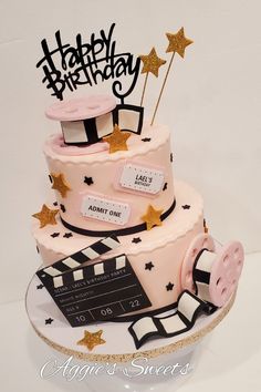 a pink and black birthday cake sitting on top of a white plate with gold stars