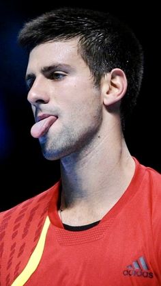 a man sticking out his tongue while wearing a red shirt